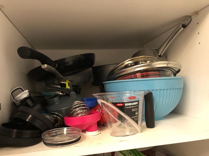 A snapshot of a cluttered cabinet before using the pan organizer, showing a disorganized space.