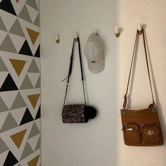gold-tone and white wall hooks with two purses hanging on the wall