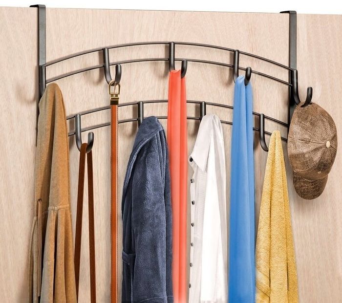 Over-the-door hanger with hooks displaying various items: a beige coat, a brown belt, a blue robe, a white shirt, a red scarf, a blue scarf, and a tan hat