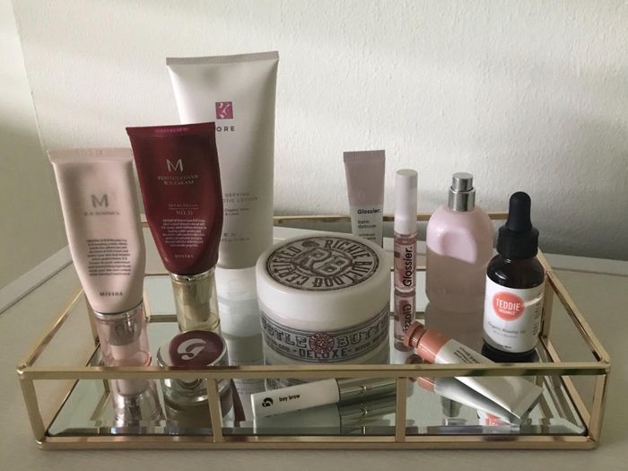 A reviewer’s photo of a mirrored and gold-trimmed tray with cosmetics placed on it.