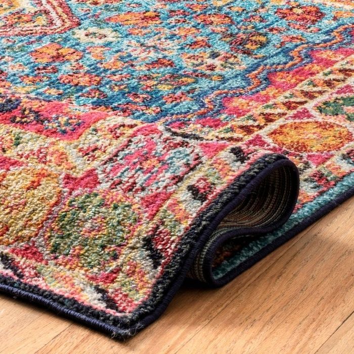 A decorative rug with detailed patterns, partially rolled up on a wooden floor