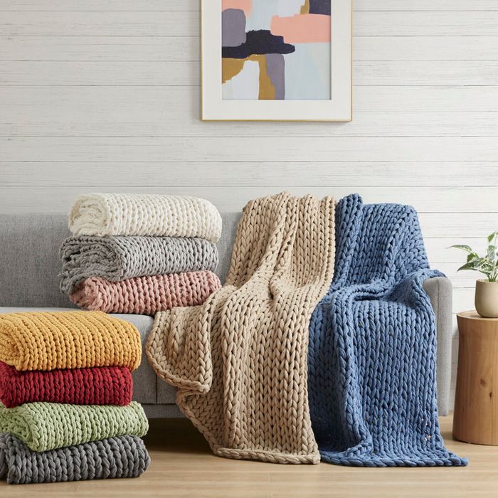 A stack of assorted knit blankets arranged on a chair for home décor