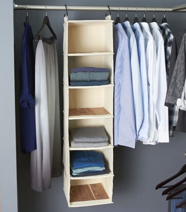 A hanging organizer neatly arranged with clothes inside a closet.