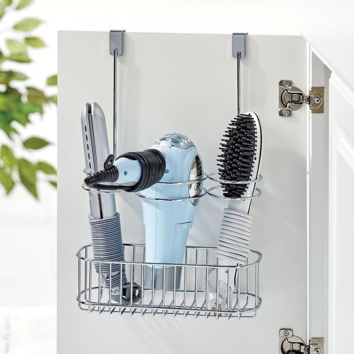 The over-the-door organizer is shown hanging on a cabinet door, holding a hair dryer, curling iron, and brush, making it an ideal solution for keeping hair tools organized and easily accessible.