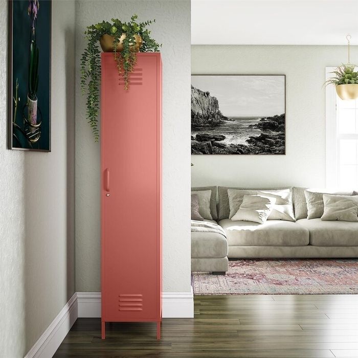 A modern living room with a pink, freestanding metal locker as a decorative piece, adorned with plants on top.