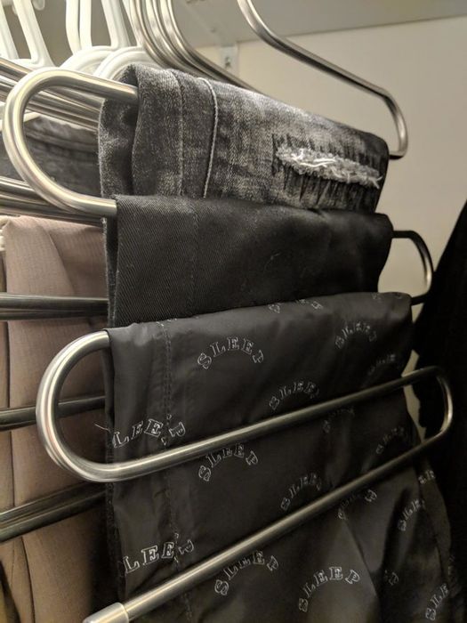 A reviewer shows an image of three pairs of pants neatly hanging from the rod, demonstrating the practicality of the hangers.