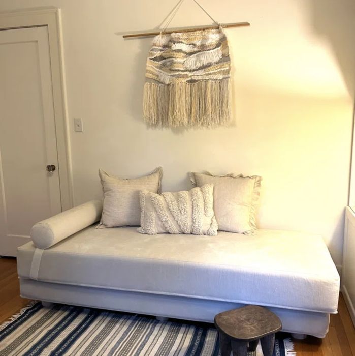 A white daybed adorned with white pillows, placed in a room