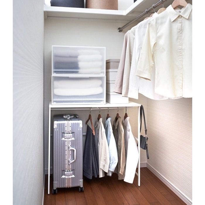 The suitcase rack in action, neatly arranged in a closet