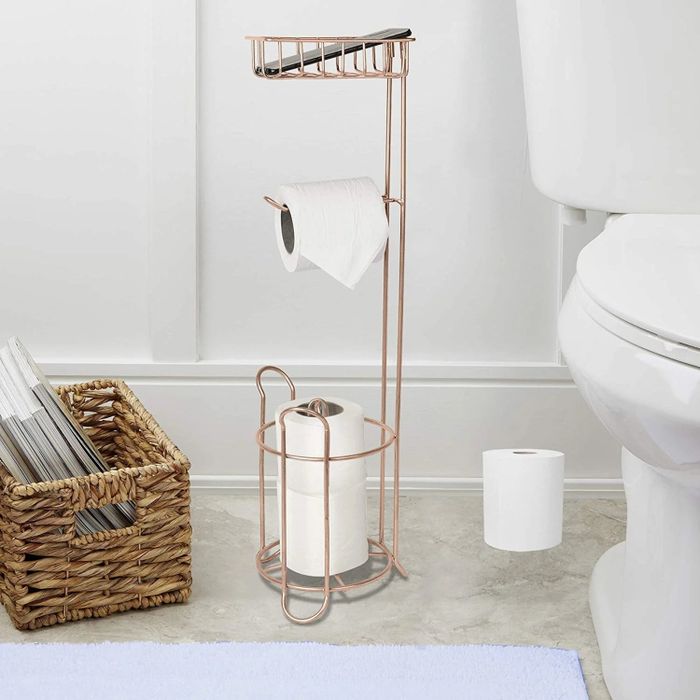 A free-standing toilet paper holder in a bathroom, neatly holding three rolls of toilet paper for easy access.