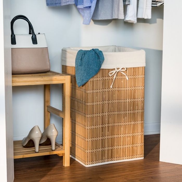 A bamboo laundry hamper with a lining, placed next to a shoe rack