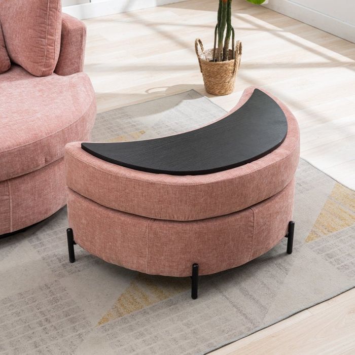 A sleek pink curved ottoman with a black top and wooden legs, positioned next to a coordinating armchair in a living room setup