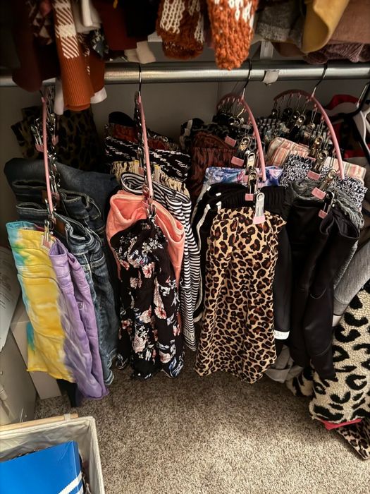 Clothes hanging in a closet, including a mix of patterned pants and shorts like leopard print, floral, stripes, and denim