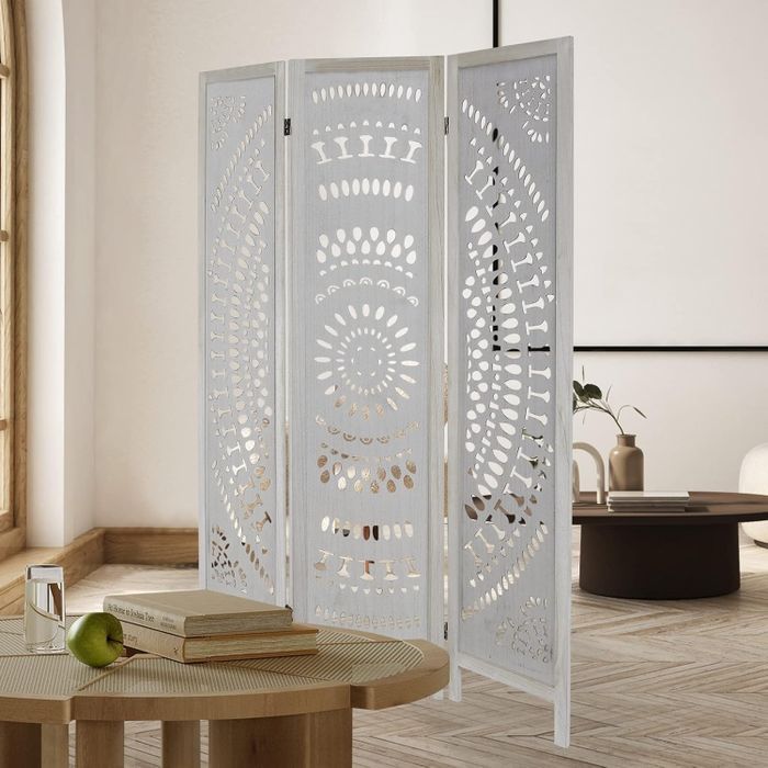 A decorative room divider featuring intricate cut-out designs, situated in a modern living area with minimal furnishings