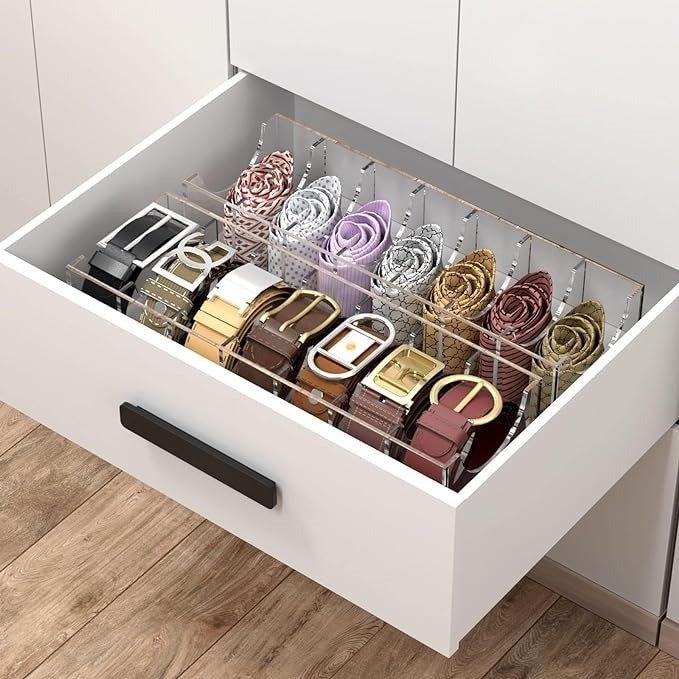 A neatly arranged drawer displaying several belts and scarves, organized in clear compartments for a stylish and efficient storage solution