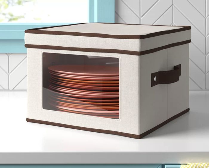 A fabric storage bin filled with neatly stacked plates.