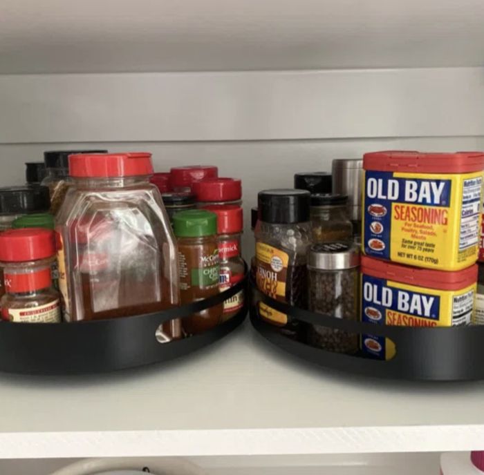 Two rotating kitchen racks filled with condiments inside a cabinet.
