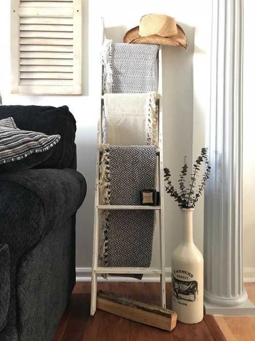 The ladder is propped against a wall, with a blanket draped over each rung in a cozy living room setting