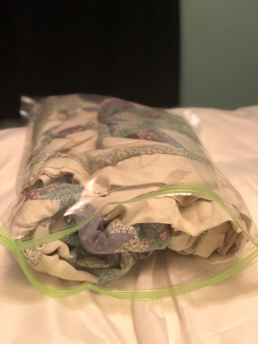 A quilt neatly stored inside a large, transparent vacuum-sealed bag, placed on a bed