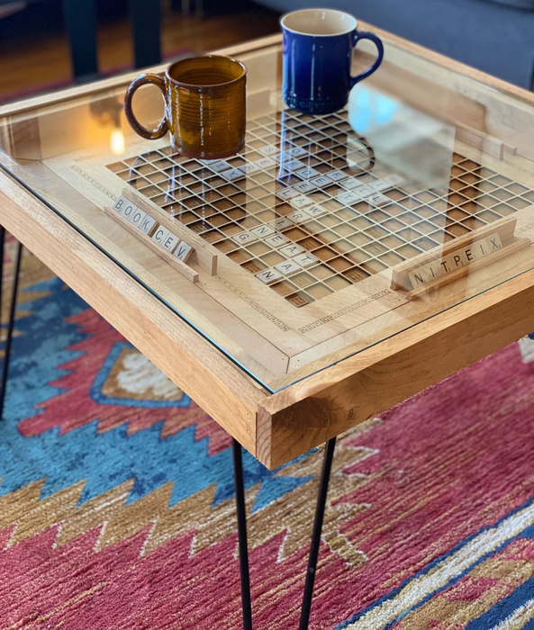 The Scrabble coffee table with a glass top, holding two mugs.