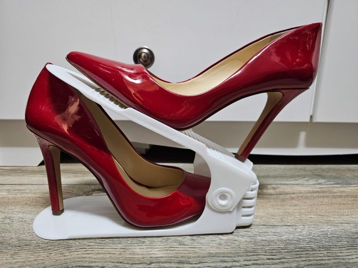 A pair of red high-heeled shoes showcased on a white shoe storage unit