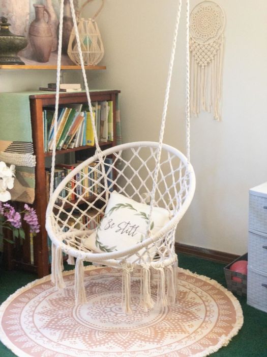 A reviewer's white macrame swing with a plush white pillow, gracefully suspended in a cozy corner.