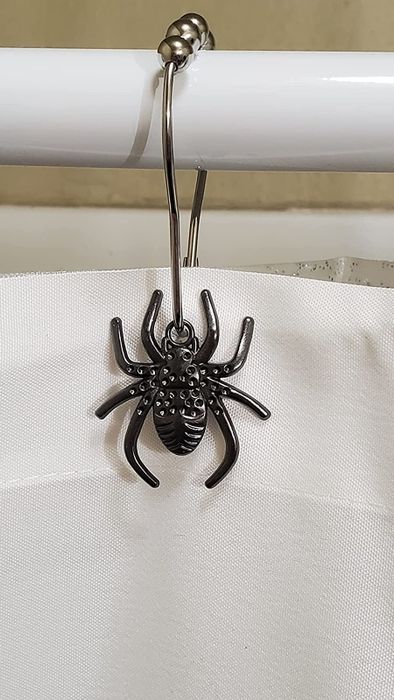 A close-up of the spider shower hooks on a reviewer's shower curtain