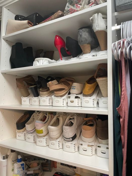 Multiple shelves in a closet filled with a variety of footwear, such as high heels, sneakers, sandals, and boots