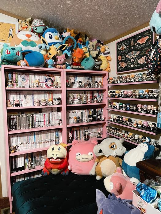 A bookshelf brimming with manga and various plush toys