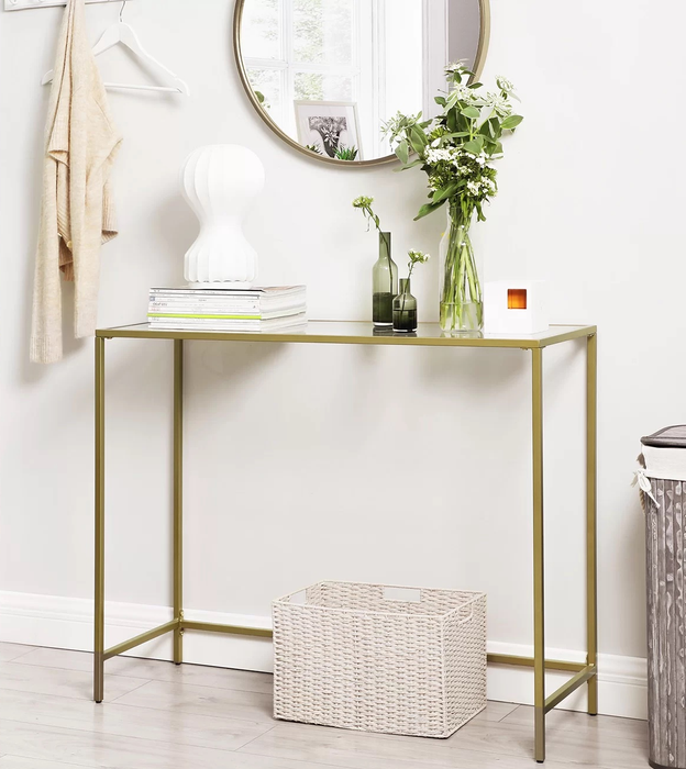 The gold console table, adorned with vases, magazines, and other small decorative objects.