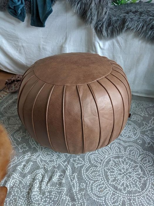 A round, brown pouf adorned with a subtle vertical line pattern encircling it.