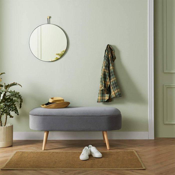 the storage bench positioned near the door, topped with a hat