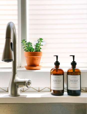 Two amber bottles placed on a reviewer's kitchen sink, each with a label indicating its contents.