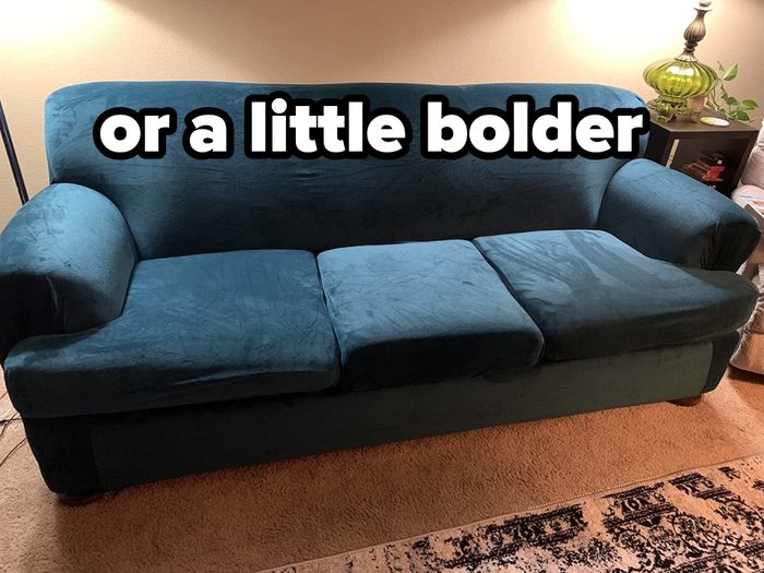 A reviewer's blue stretch velvet sofa cover on a large couch with overlaid text that reads