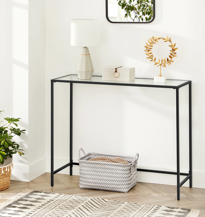 The black console table, featuring a lamp, box, and a small statue.
