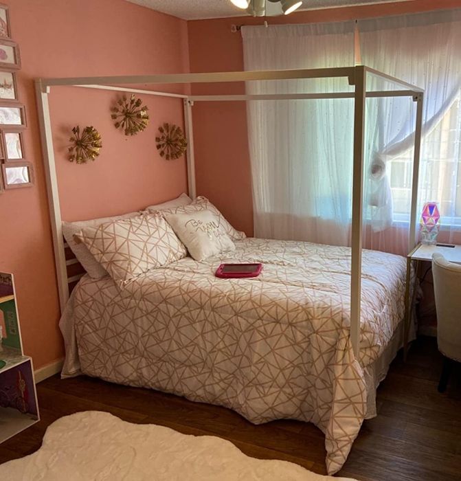 A reviewer's white canopy bed displayed in a bright, airy room.