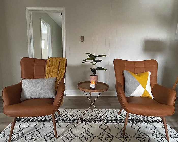 a reviewer photo of the pair of faux leather chairs adorned with pillows and throw blankets