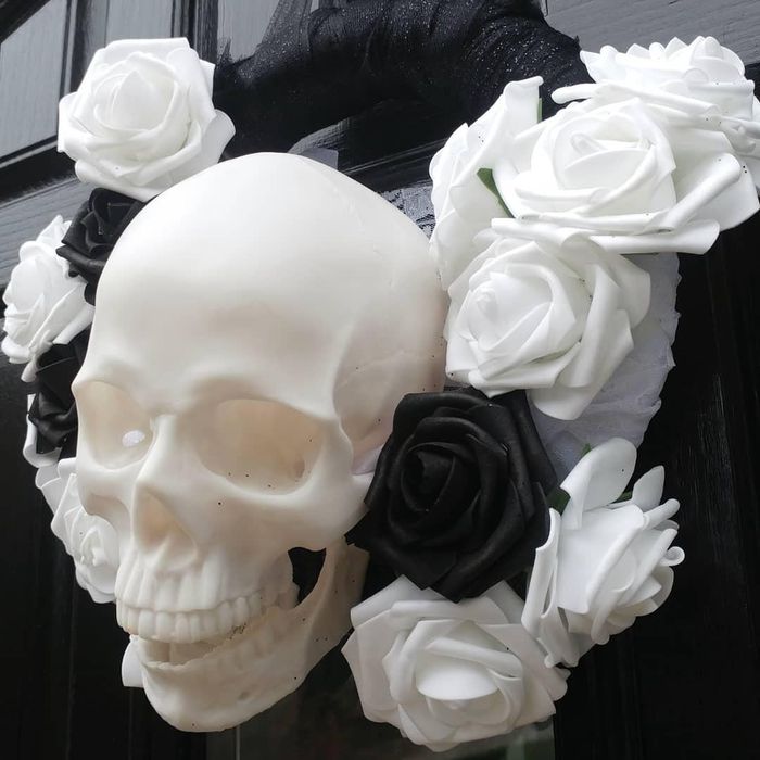 the skull placed in the midst of a black and white rose wreath