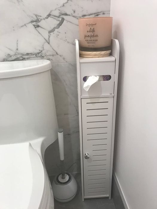 The white cabinet with a toilet paper dispenser attached
