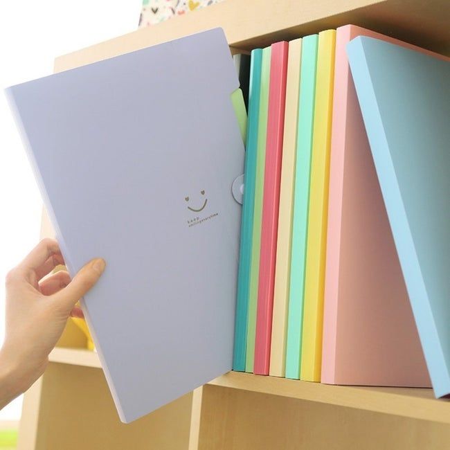 A purple accordion file folder with a smiley face, being pulled out from a bookshelf.