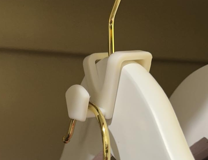 Close-up view of a white clothes hanger with an attached hook