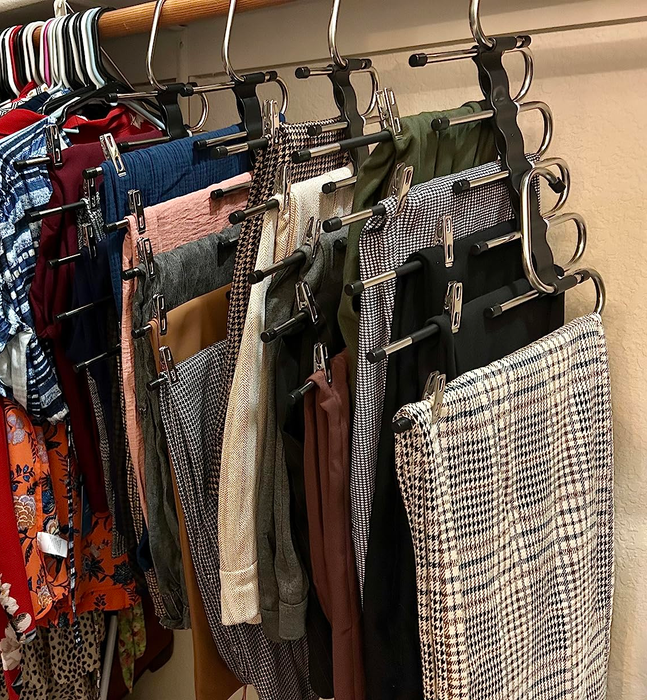A closet showcasing neatly hung pants in various patterns and solid colors, with shirts hanging in the background