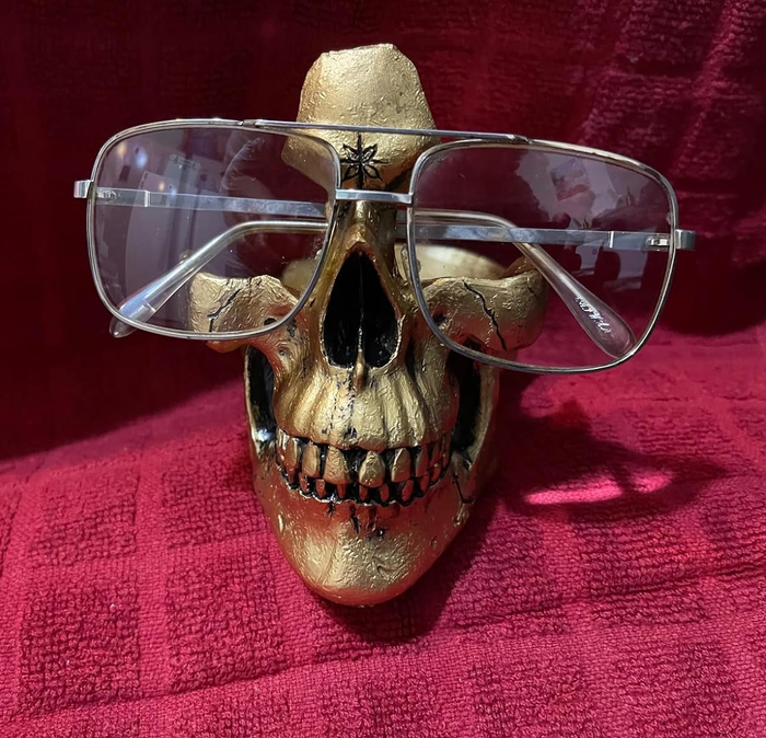 a gold skull holding a reviewer’s glasses on its surface