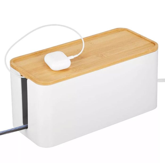 A sleek cable management box with a wooden lid, with a white charging cable running through the top for easy access.