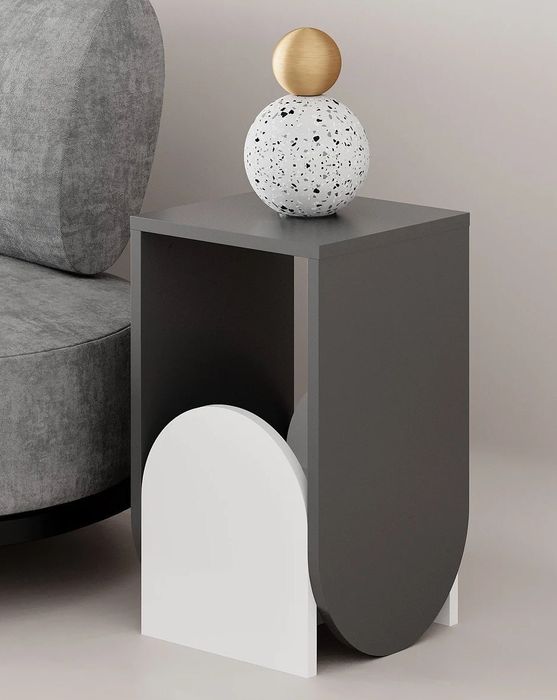 The gray and white side table next to a gray couch, featuring a spherical sculpture.