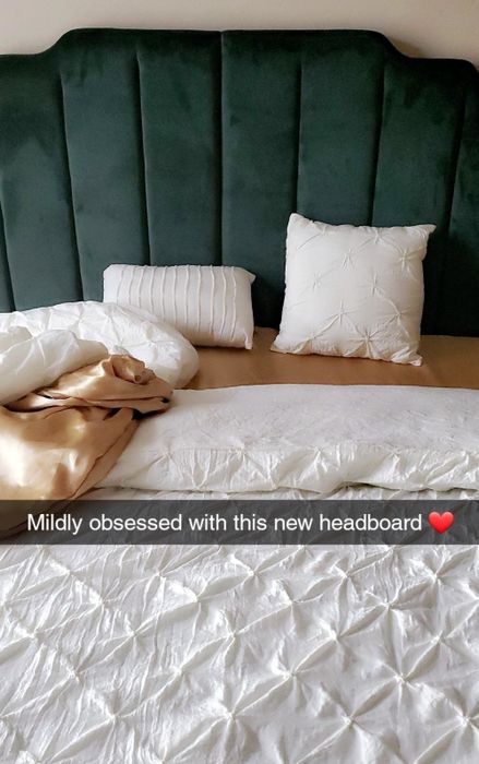 a reviewer photo showcasing a deep green velvet headboard with text overlay reading 'mildly obsessed with this new headboard'