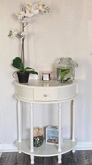 Reviewer photo of the white table adorned with plants, a candle, and a few other decorative items.