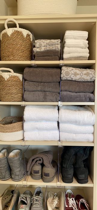 Shelves neatly organized with folded towels, baskets, boots, and shoes