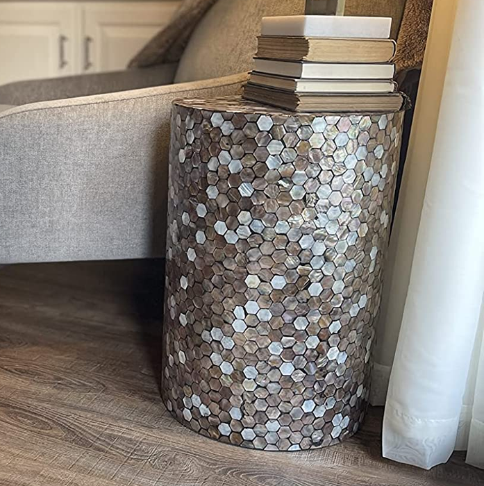 A reviewer’s photo of the end table with a stack of books beside an armchair.