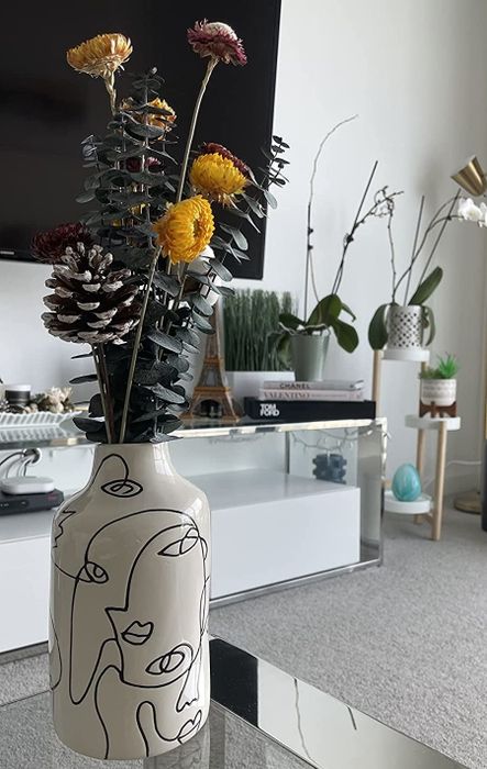 A reviewer's image of the vase filled with dried flowers on a cozy living room table.