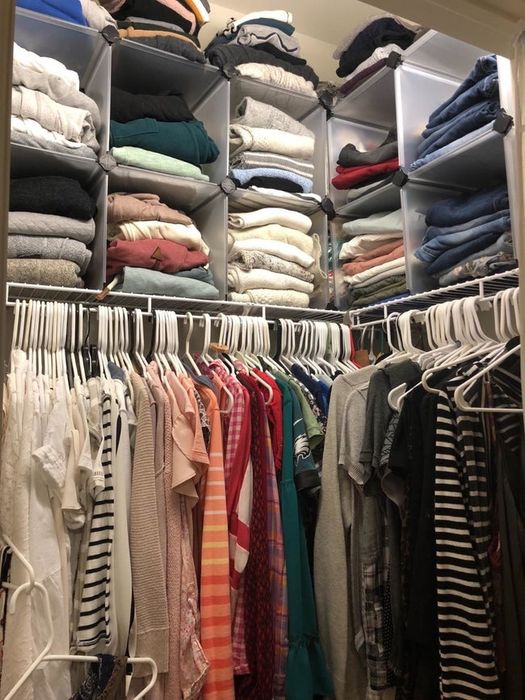 A reviewer's photo of a closet where storage cubes are placed on the top shelf, creating extra room for clothes below